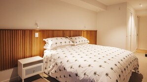 Ein Schlafzimmer mit einem Bett, einem Nachttisch und einem an der Wand befestigten Regal.