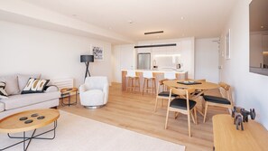 Relax in a spacious living area with a sofa set, coffee table, and armchair. Enjoy meals at the dining table and kitchen area with a refrigerator and sink.