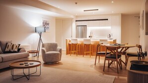 Ein modernes Wohnzimmer mit einer Couch, einem Sessel, einem Couchtisch und einem Essbereich mit Holzkästen und einem Tisch.