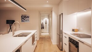 Eine moderne Küche mit weißen Schränken, einem Edelstahlkühlschrank und einem eingebauten Backofen.
