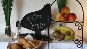 En morgenmadsopstilling med brød, frugt og et lys.