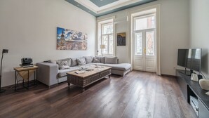 Un salon avec un canapé d’angle gris, une table basse en bois et un téléviseur à écran plat posé sur un meuble noir.