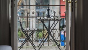 Une vue à travers une porte ornée d’une rambarde en métal, avec une table sur laquelle se trouvent des verres et une bouteille.