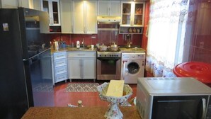 Une cuisine compacte équipée d’un réfrigérateur, d’une cuisinière, d’un four à micro-ondes et d’un lave-linge.
