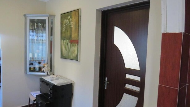 Un couloir avec une porte en bois dotée d’une grande découpe semi-circulaire blanche, un tableau encadré accroché au mur et un petit bureau avec une chaise.