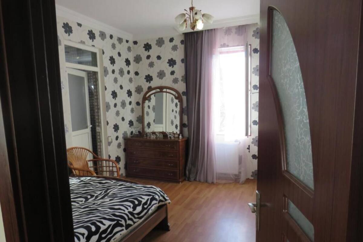 Un dormitorio con cama, cómoda, silla y espejo.