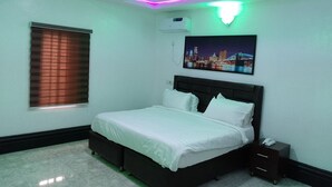 A bedroom with a bed, a nightstand, a wall-mounted air conditioner, and a cityscape painting. - FMMM1 (Agbor)