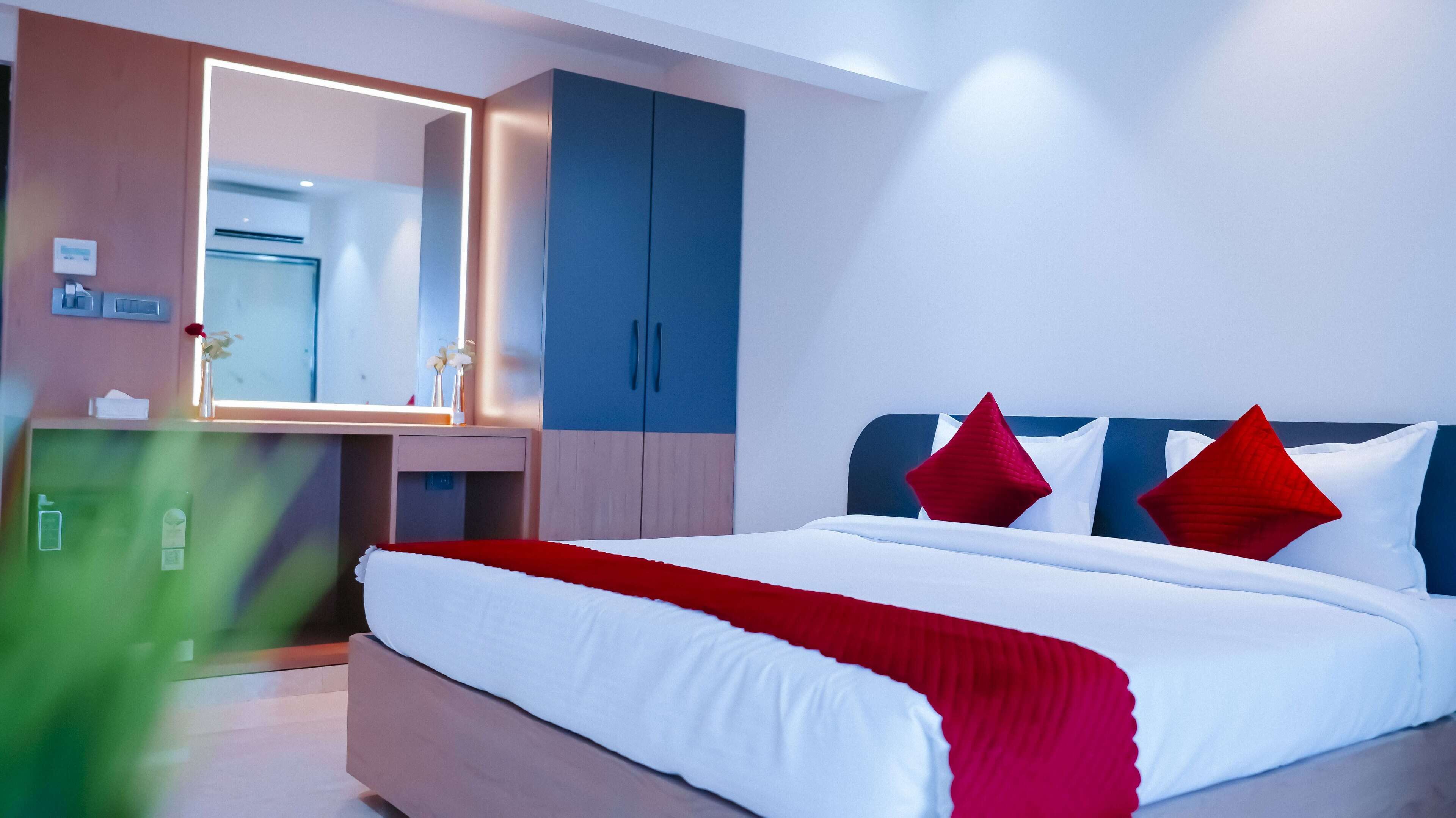 Una habitación de hotel moderna con una cama grande, un armario empotrado, un espejo y una mesita de noche.