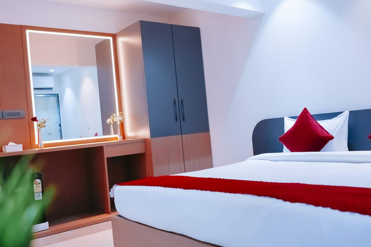 A hotel room with a bed, a wardrobe, and a mirror.