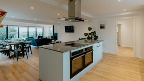 A modern kitchen with a central island, built-in oven, and a dining area with a table and chairs.