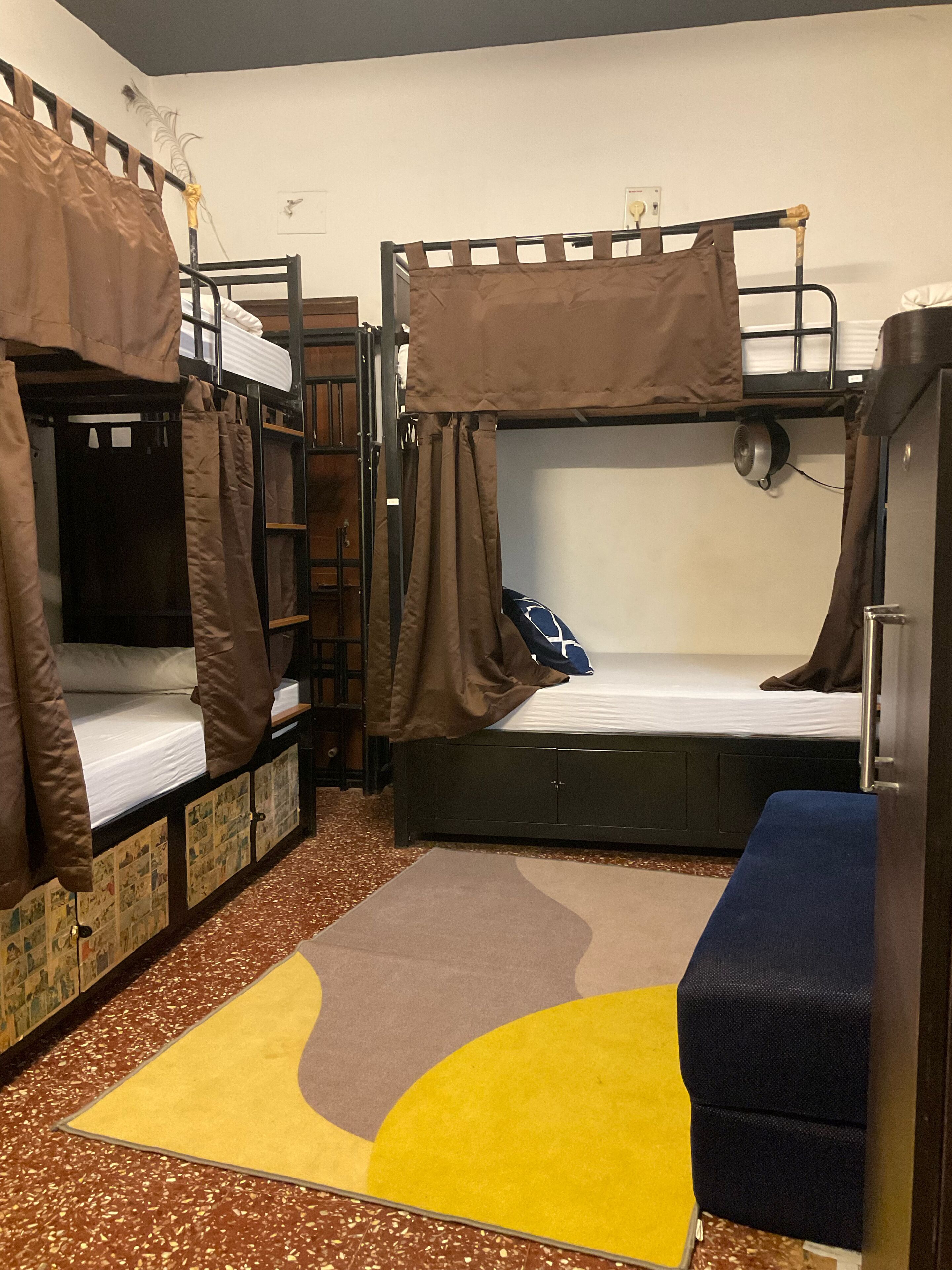 A dormitory room with bunk beds, a small desk, and a chair.