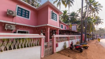 Un bâtiment rose doté de climatiseurs, une enseigne indiquant qu’il s’agit d’une auberge de jeunesse, et une entrée fermée par un portail.