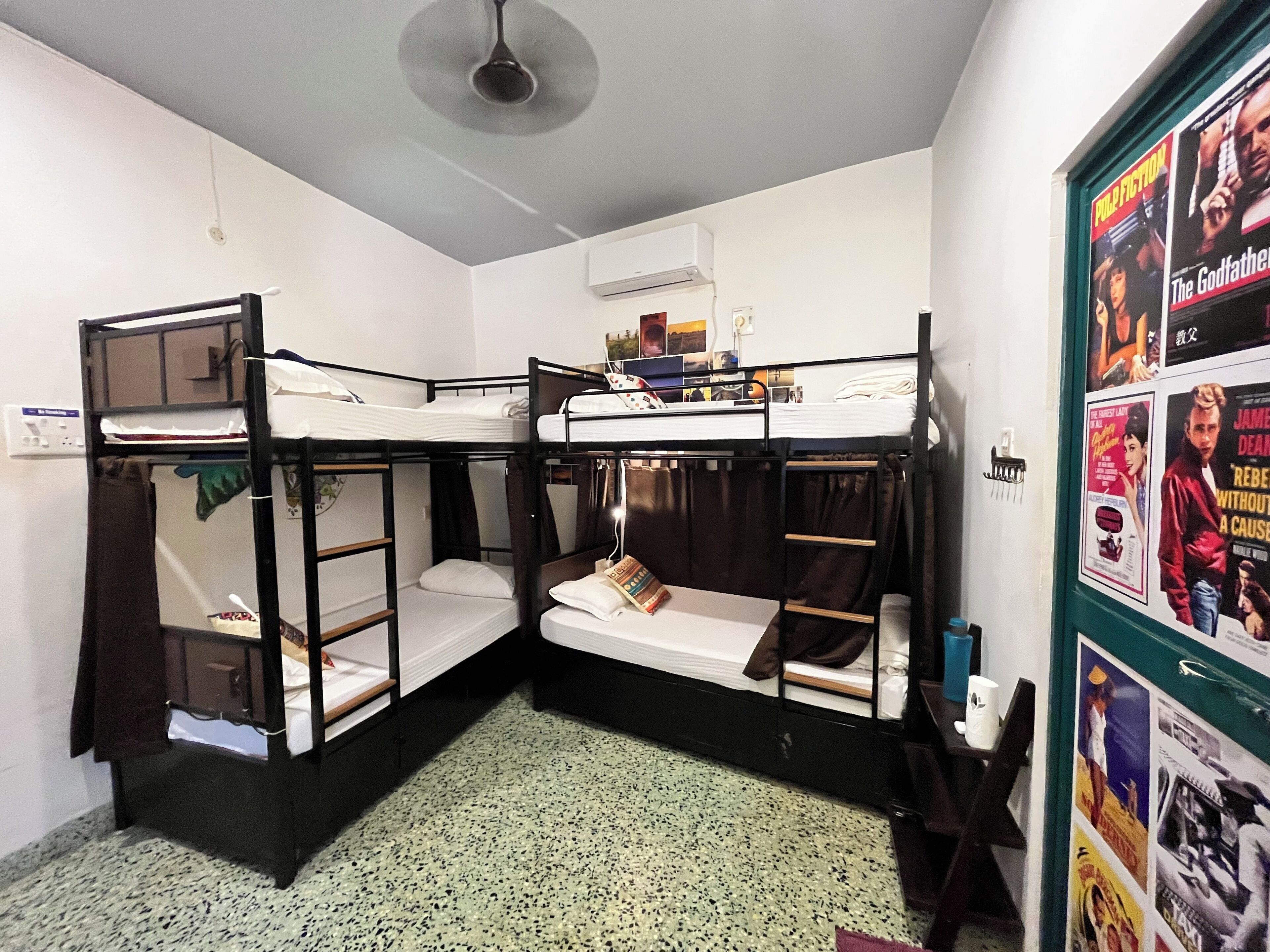 Un dormitorio con literas, dos literas, un ventilador de techo y un cartel en la pared.