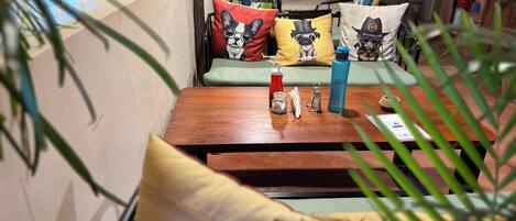 A cozy seating area with a wooden table, a green sofa, and colorful cushions.