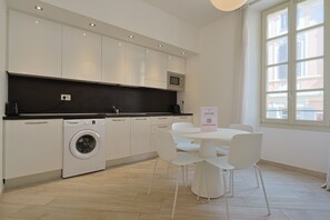 A modern kitchen with a washing machine, a microwave, and a dining area with a table and chairs. - 2D Tony Allard (Cannes)