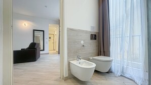 A modern bathroom with a bidet, toilet, and a mirror.