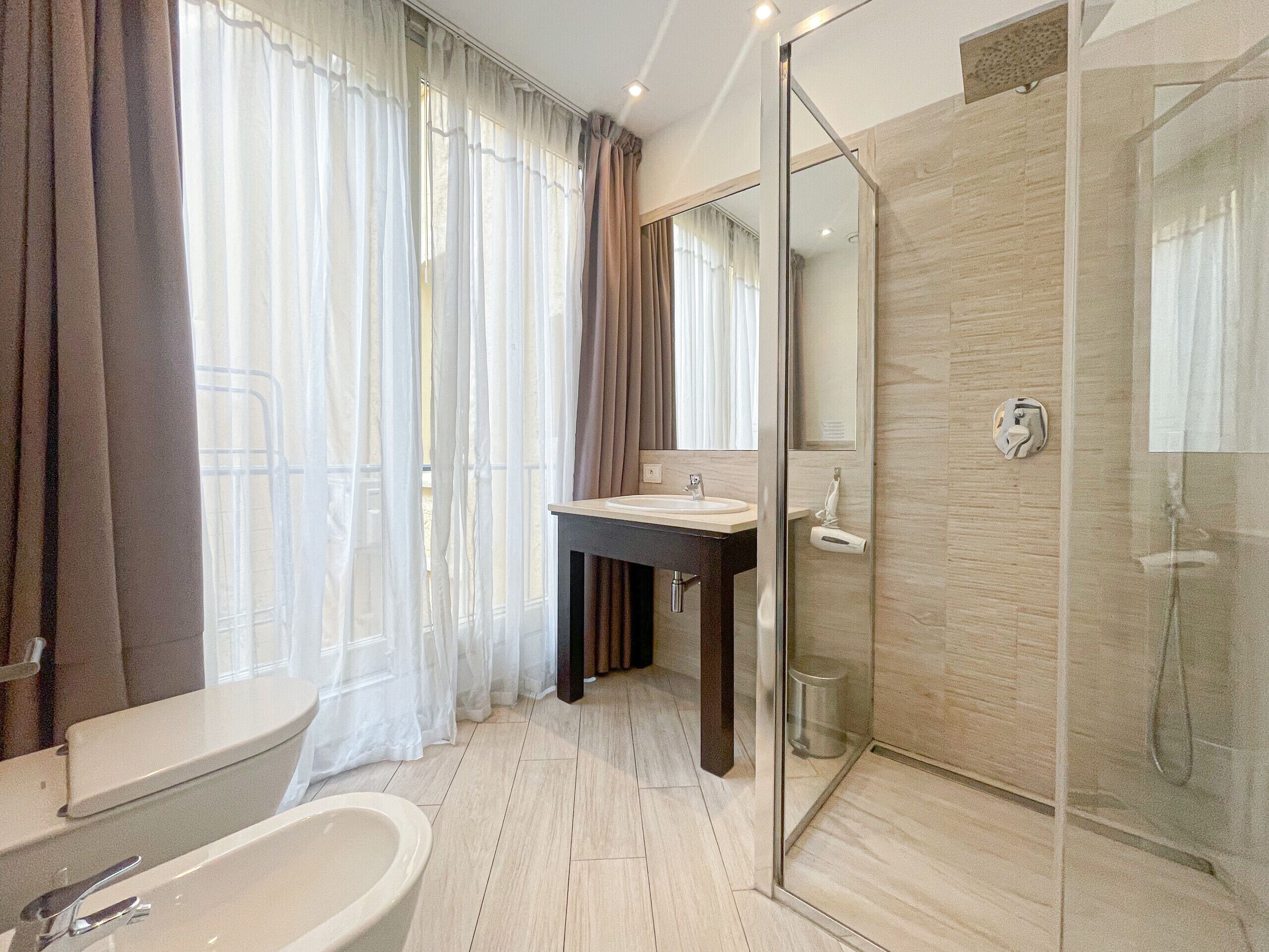 A modern bathroom with a bathtub, a sink, and a glass-enclosed shower.