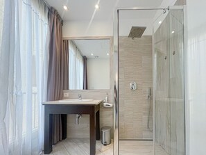 Un bagno moderno con box doccia in vetro, un mobile lavabo e uno specchio.