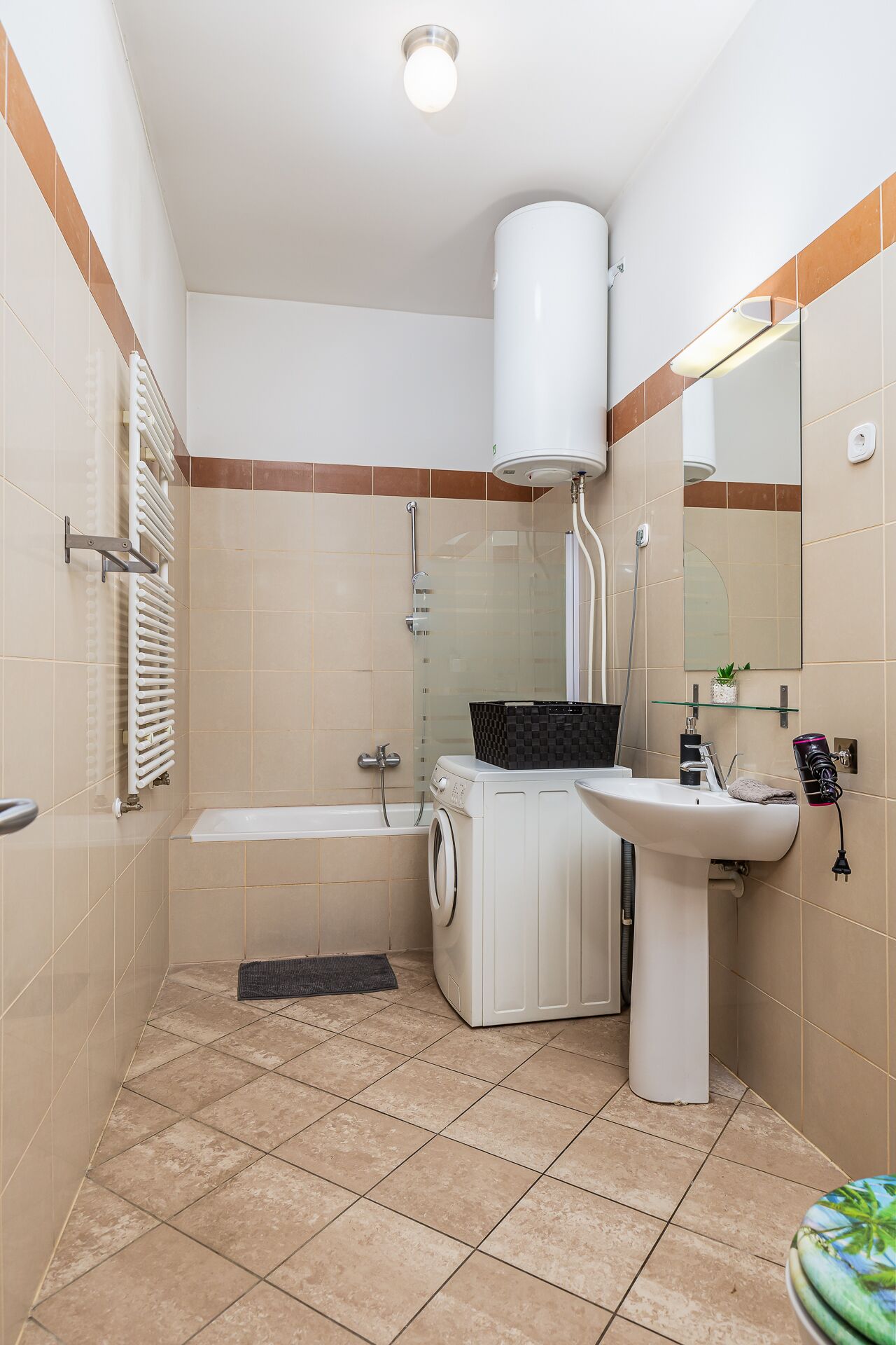 A compact bathroom with a washing machine, a sink, a toilet, and a shower.