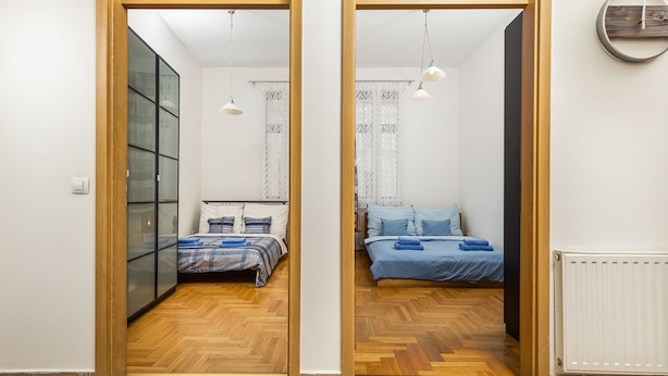 A room with two beds, wooden flooring, and a radiator. - Venus Apartments - Gozsdu Court III (Budapest)