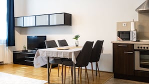 A modern kitchen with a dining table, chairs, a TV, and a microwave. - Venus Apartments - Gozsdu Court III (Budapest)