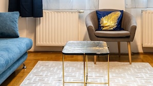 A living room with a sofa, a coffee table, and a chair with a decorative pillow. - Venus Apartments - Gozsdu Court III (Budapest)