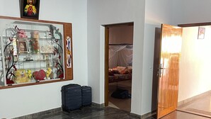 Eine Hotelhalle mit einem Glastisch, einer hölzernen Bank, einem Deckenventilator und einer Tür zu einem Schlafzimmer.
