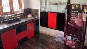 Eine Küche mit roten und schwarzen Schränken, einem Gasherd und einem Kühlschrank.