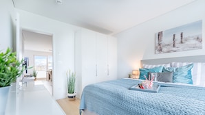 Un dormitorio moderno con una cama grande, una mesita de noche con lámpara y vistas al exterior.