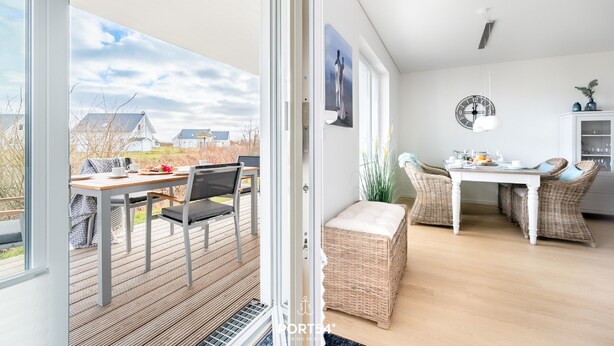 Una cocina moderna con mobiliario de mimbre, una mesa de comedor y vistas al exterior.