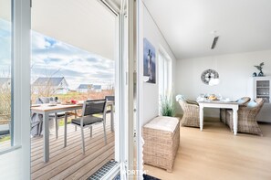 A modern kitchen with wicker furniture, a dining table, and a view of the outdoors. - Stjernehus - Ground Floor, Infrared Sauna, Fireplace, Washing Machine, Terrace (Olpenitz)