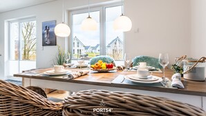 Una cocina moderna con una isla central, ventanas amplias y lámparas colgantes.