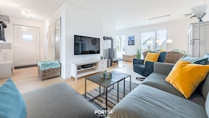 Una sala moderna con un sofá gris, un televisor y una cesta de mimbre.