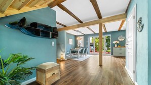 Una habitación amplia con vigas de madera, un comedor y vistas al exterior.