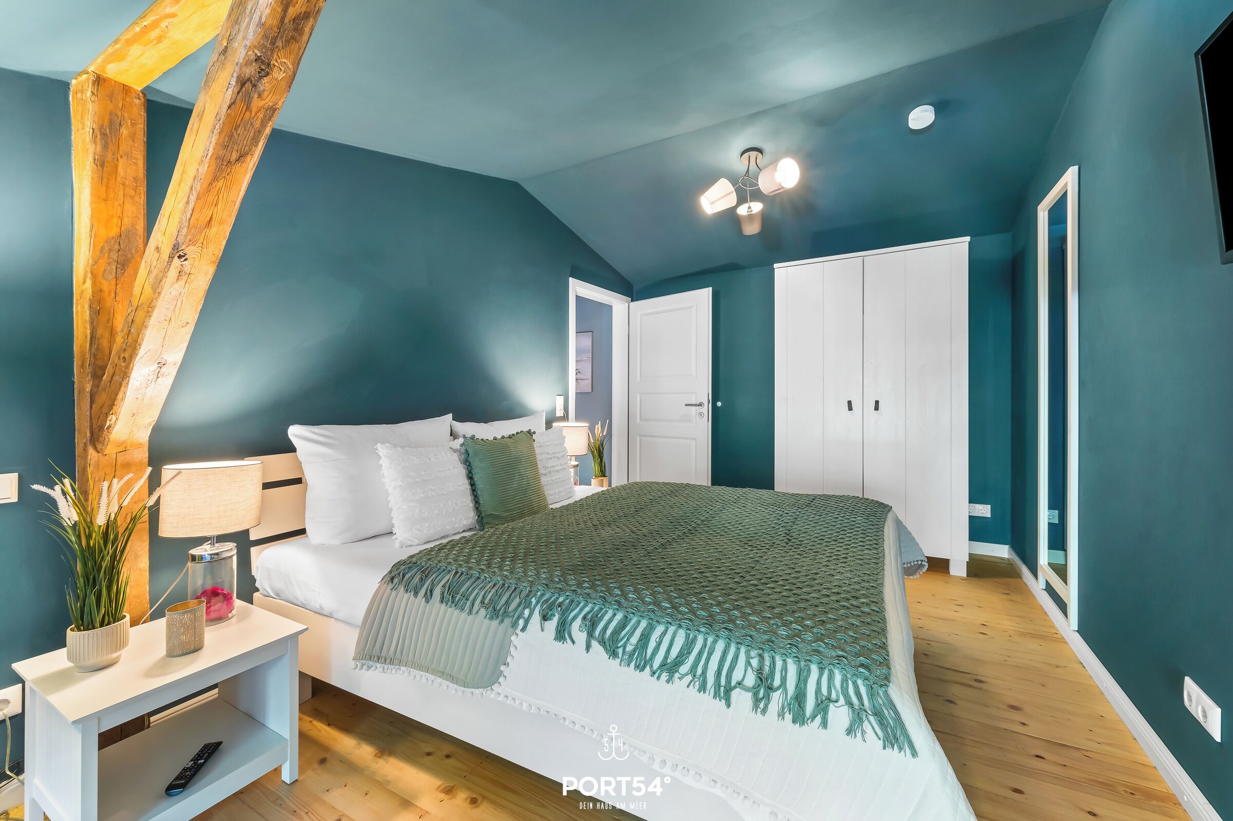 Una camera da letto con un letto, un comodino, una lampada e un'ampia finestra.