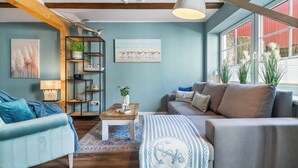 Una sala de estar con un sofá azul, un sofá gris, una mesa de centro de madera y una estantería.
