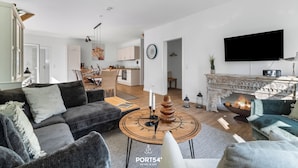 Ein modernes Wohnzimmer mit Kamin, großem Flachbildfernseher und gemütlicher Sitzecke.