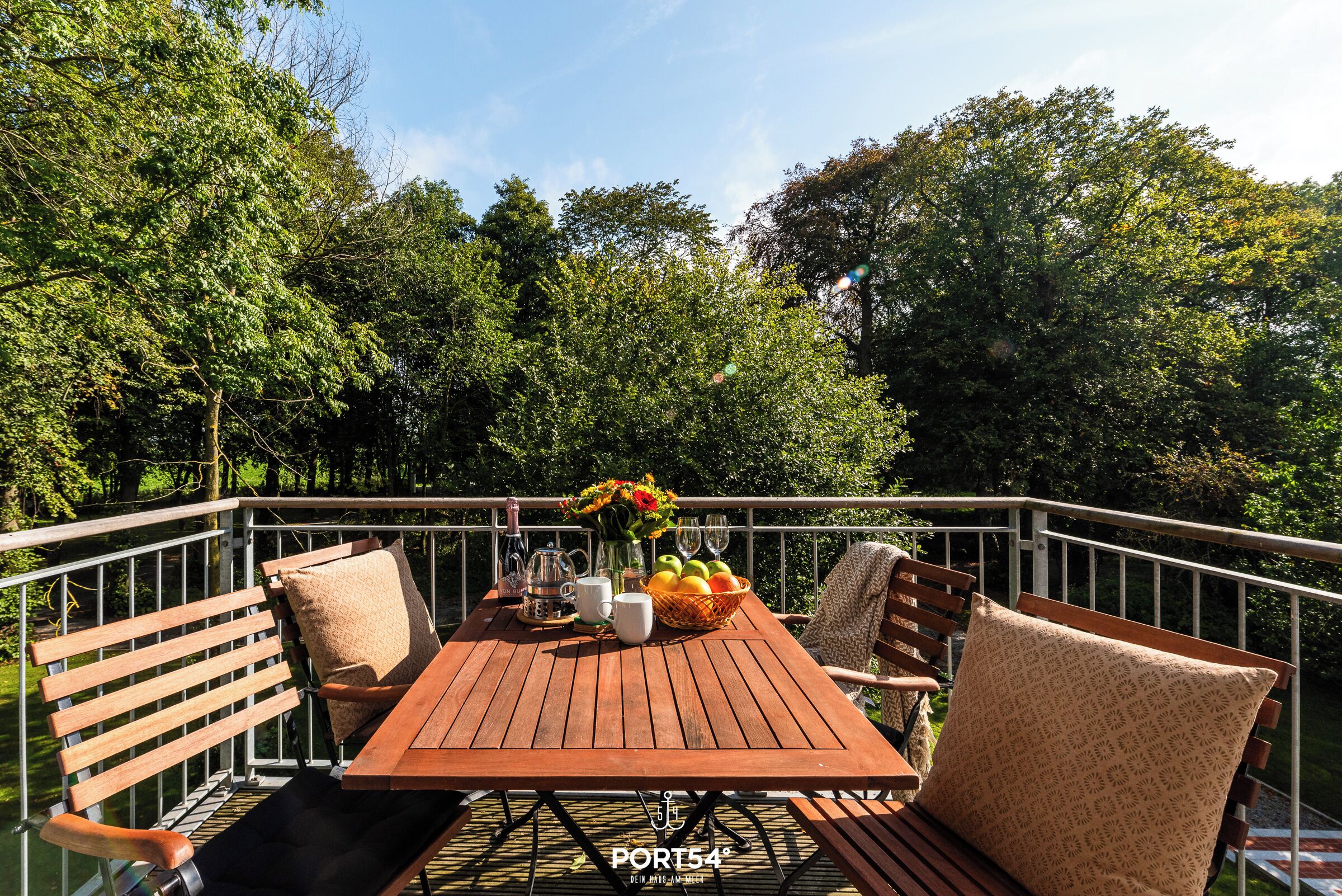 Eine Holzterrasse mit Esstisch, umgeben von Stühlen und einem Geländer.