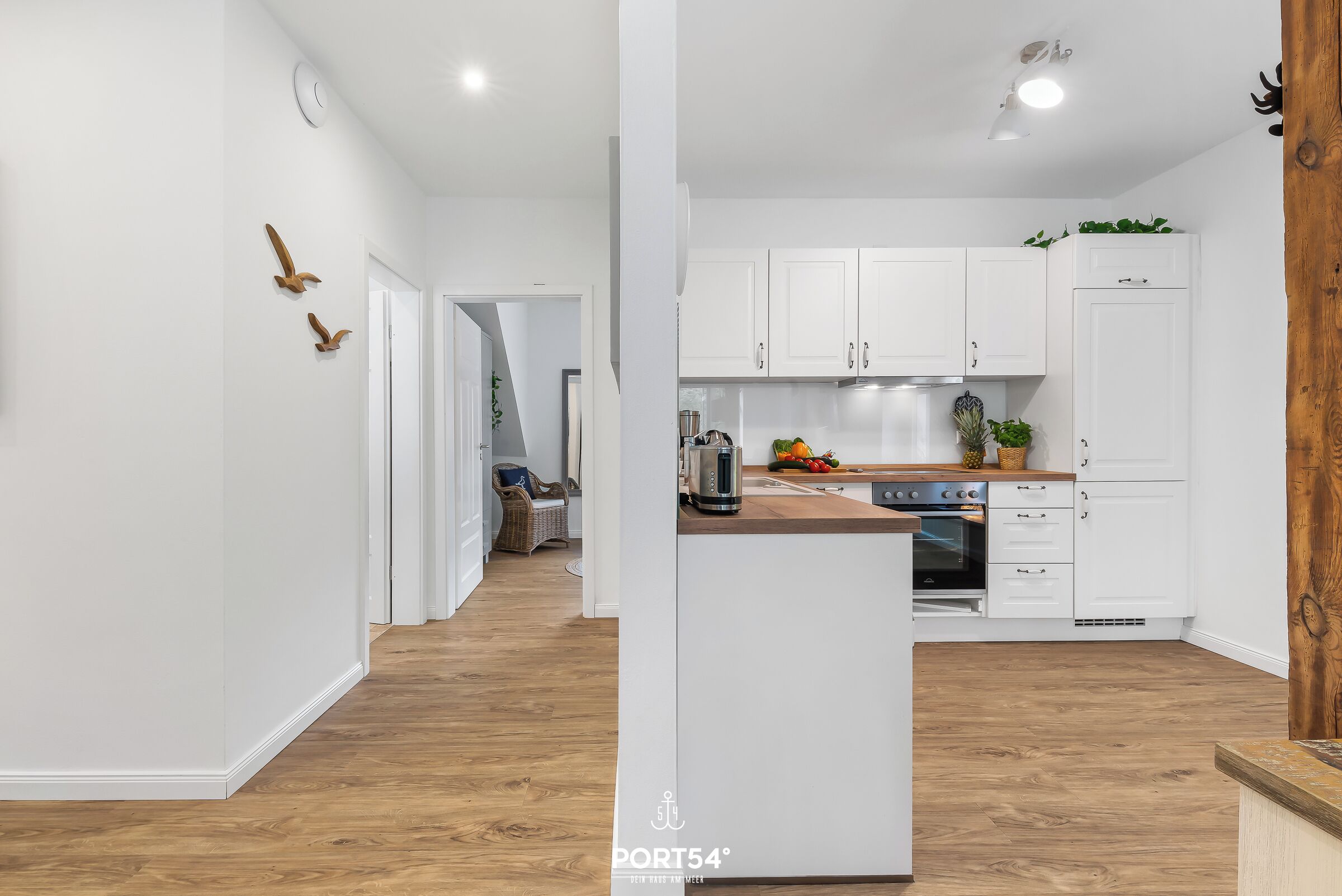 A modern kitchen with white cabinets, a wooden countertop, and a built-in oven.