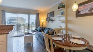 A dining area with a round table set for four, a sofa, and a balcony with a view of buildings.
