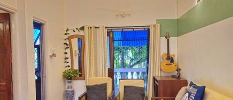 A room with a ceiling fan, a chandelier, a guitar, and a sofa with cushions.
