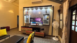 Una sala de estar con una televisión de pantalla plana montada en la pared, un sofá, una silla y una pequeña mesa.