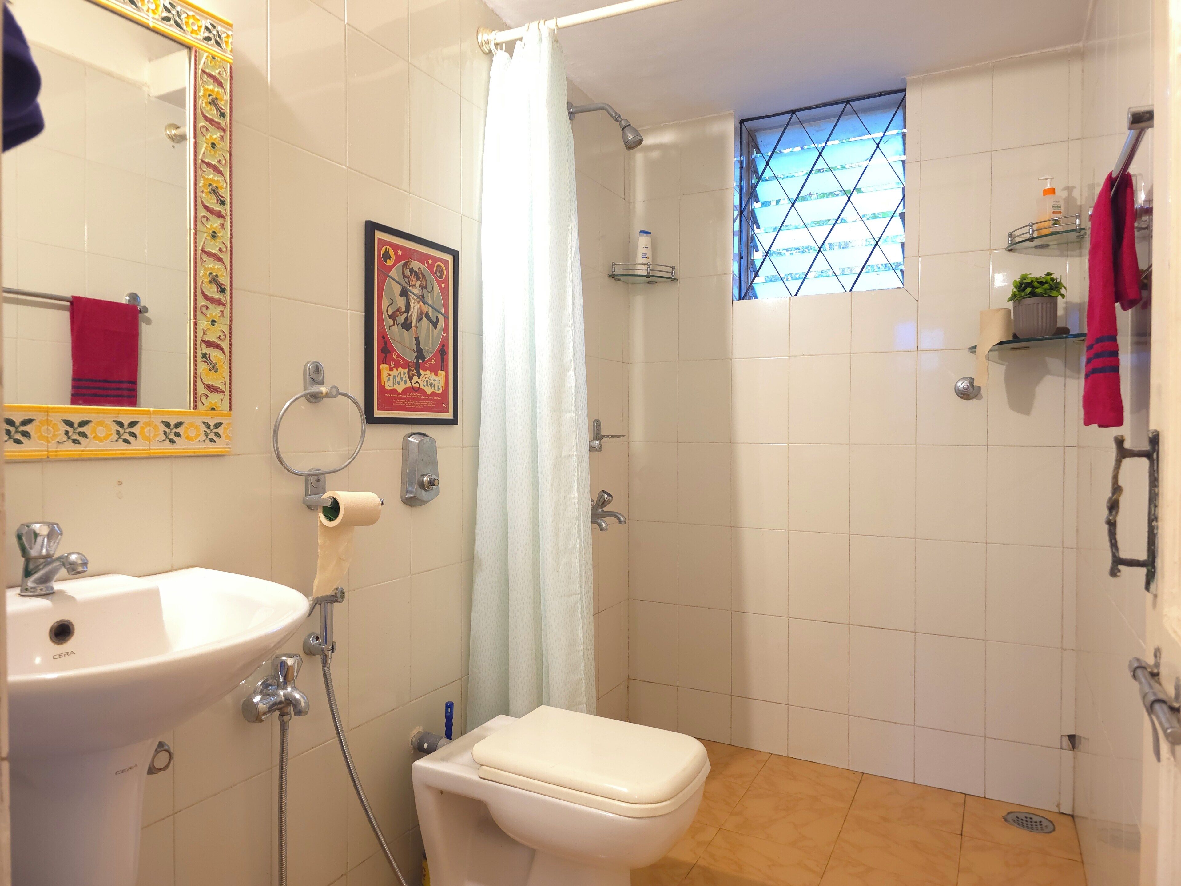 A bathroom with a sink, toilet, shower, and a window with a view.