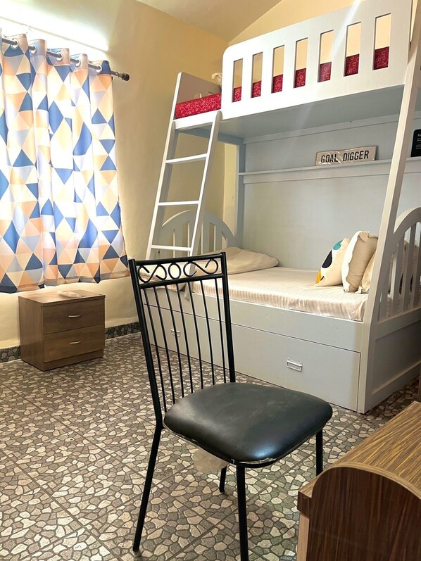A bunk bed with a ladder, a desk, a chair, and a patterned curtain. - You are the key Viila (Anjuna)