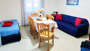 Una habitación con una mesa de comedor, sillas, un sofá, una cama y un cuadro en la pared.