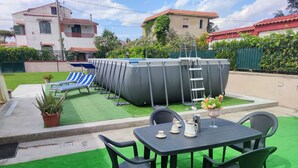 Un patio al aire libre con una mesa, sillas y una piscina.