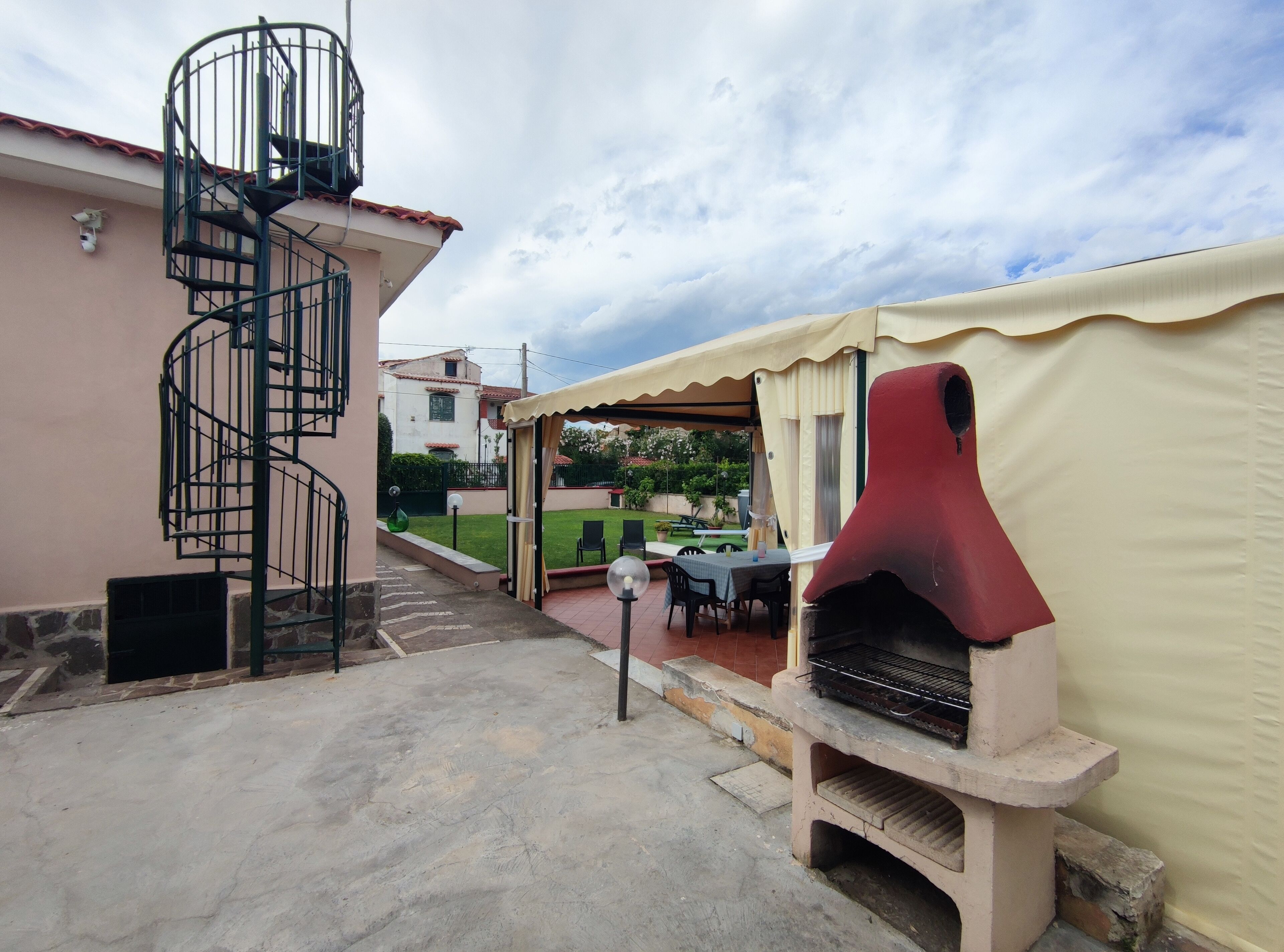 Eine Terrasse mit einer Wendeltreppe, Sitzgelegenheiten im Freien und einem Grill.