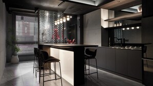 A modern kitchen with a central island, bar stools, and a large window with blinds. - Guangfa Hotel (Tainan)