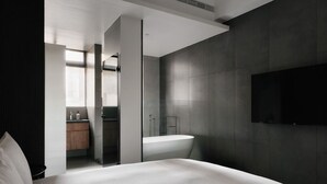 A modern hotel room with a large bed, a built-in TV, a bathroom with a bathtub, and a shower. - Guangfa Hotel (Tainan)