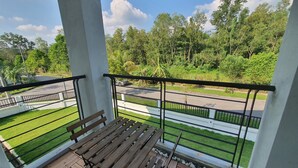 Un balcon avec des bancs en bois et une vue sur une route et la verdure.